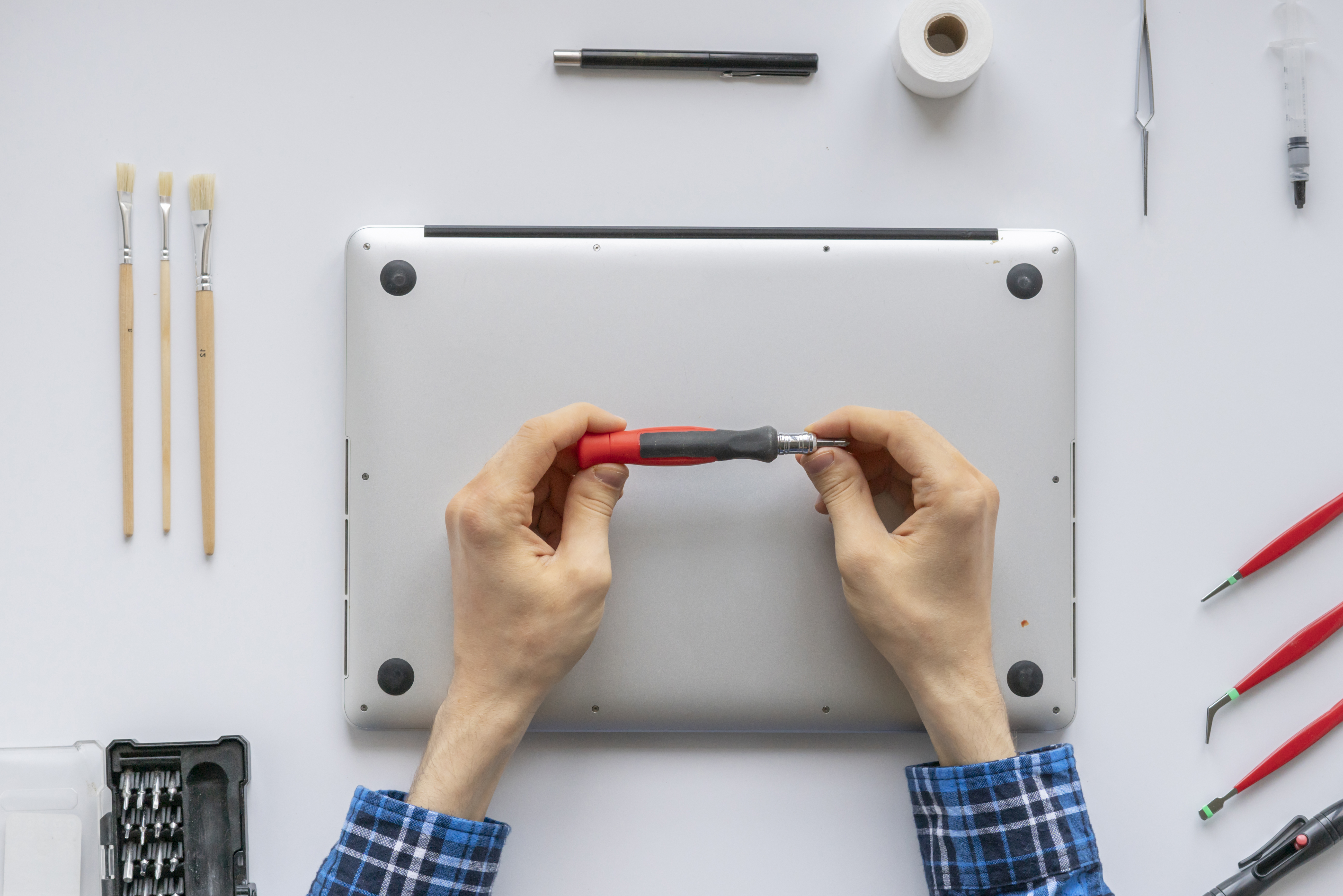 Top view of tech repairing laptop with screwdriver